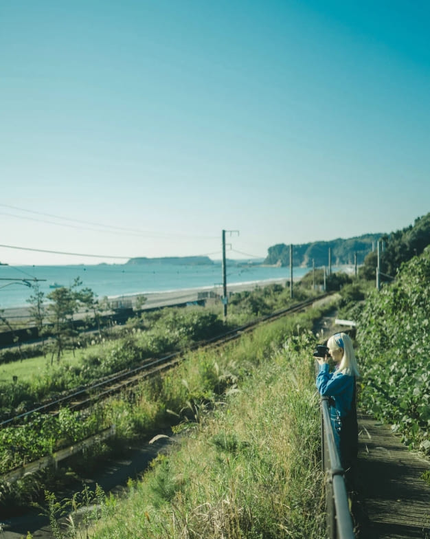 線路に向かってカメラを構える女性の写真